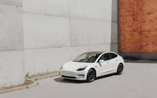 Tesla Model 3 w szerokim kadrze na tle betonowej ściany